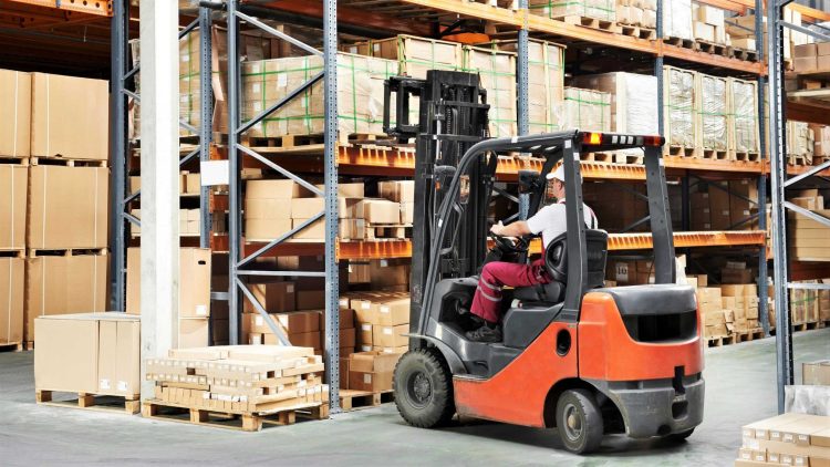 Operator using a sit-down forklift to store pallets in a warehouse