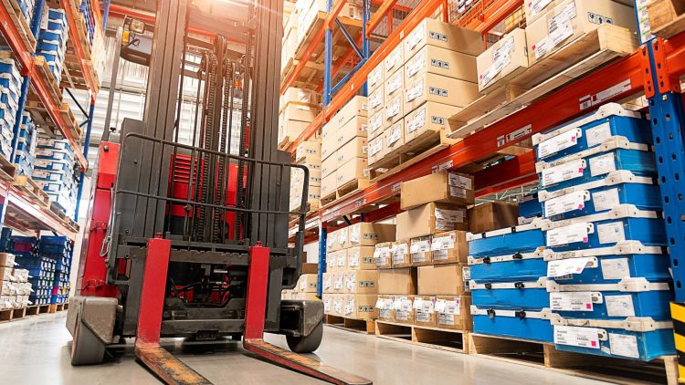 Red warehouse forklift with a 3 stage mast and cushion tires