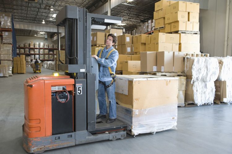 Warehouse operator standing on a stock picker forklift