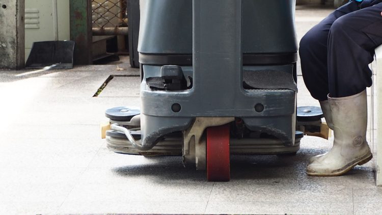 Worker leaning on a industrial floor scrubber